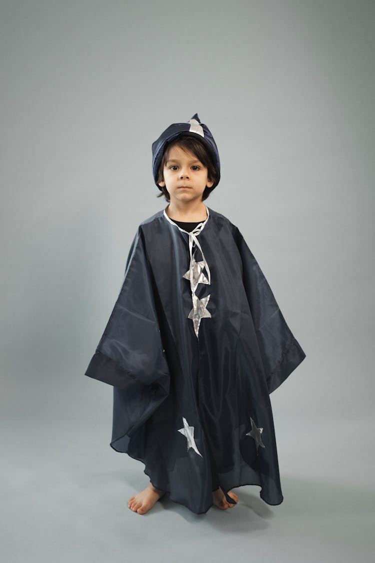 Small Boy Wearing Magician Costume Standing In Studio