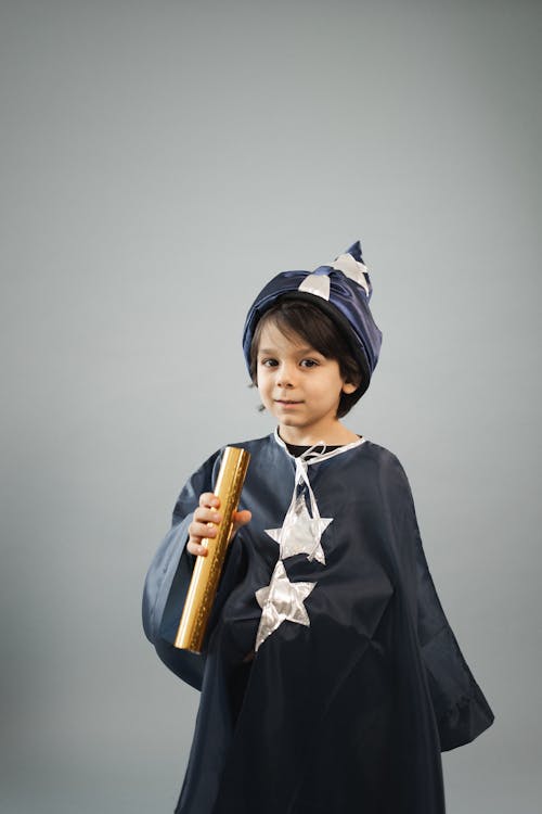Little boy wearing magician costume standing with kaleidoscope tube