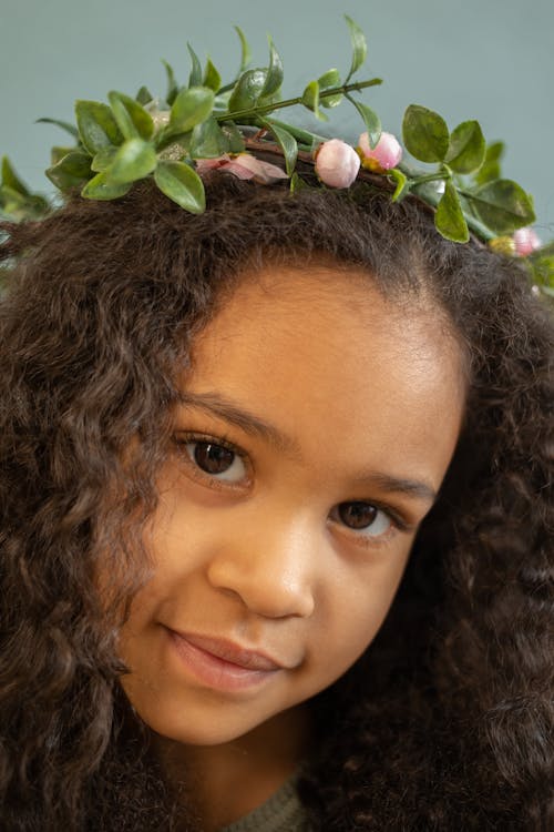 Free Charming African American girl with curly hair in floral wreath looking at camera with gentle smile Stock Photo
