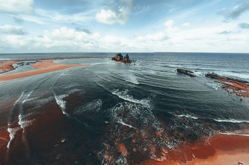 Free A stunning aerial shot of Kemasik Beach in Malaysia, showcasing waves and rocks under a cloudy sky. Stock Photo