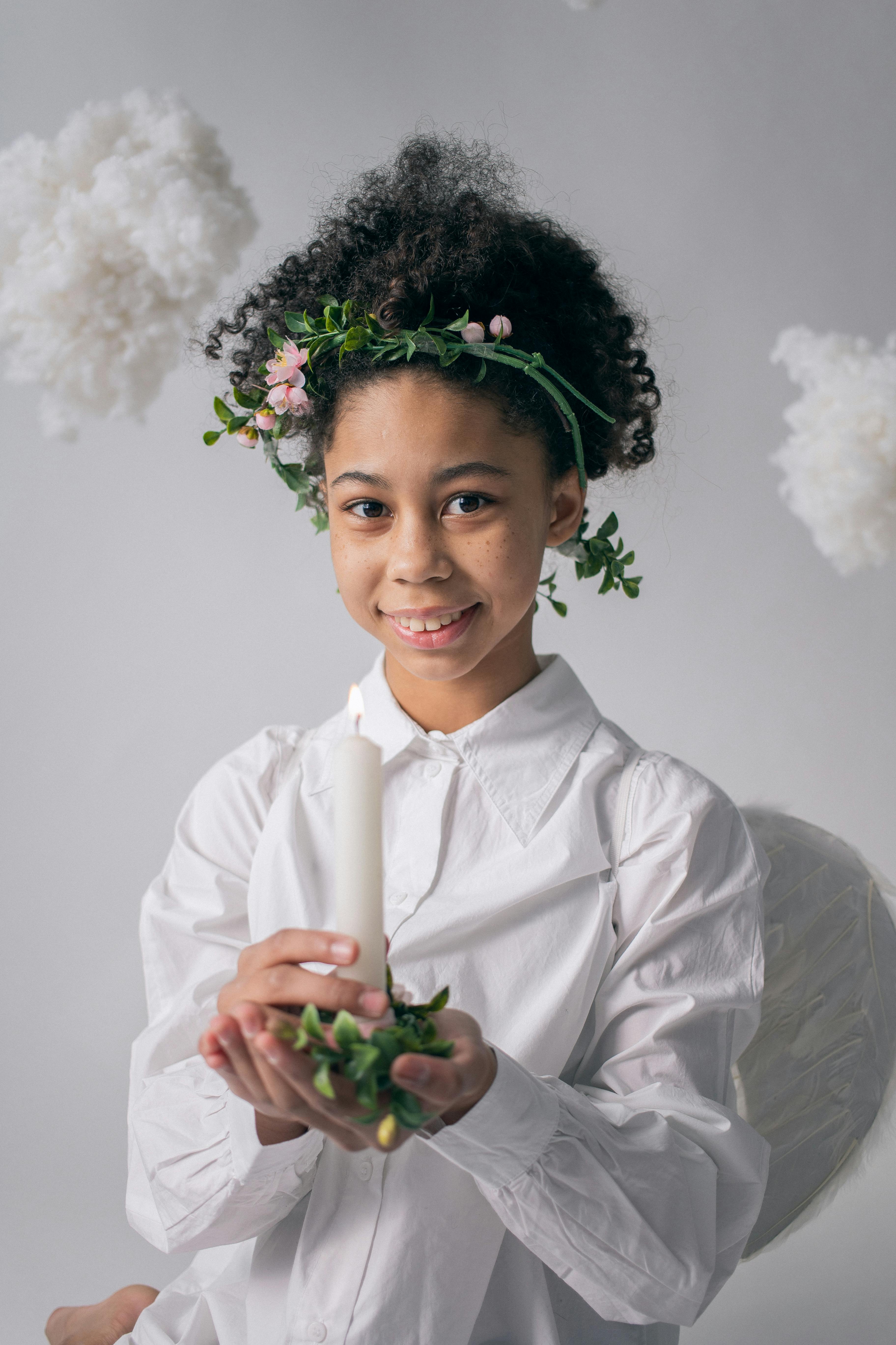 smiling black girl in angel costume with candle in candle