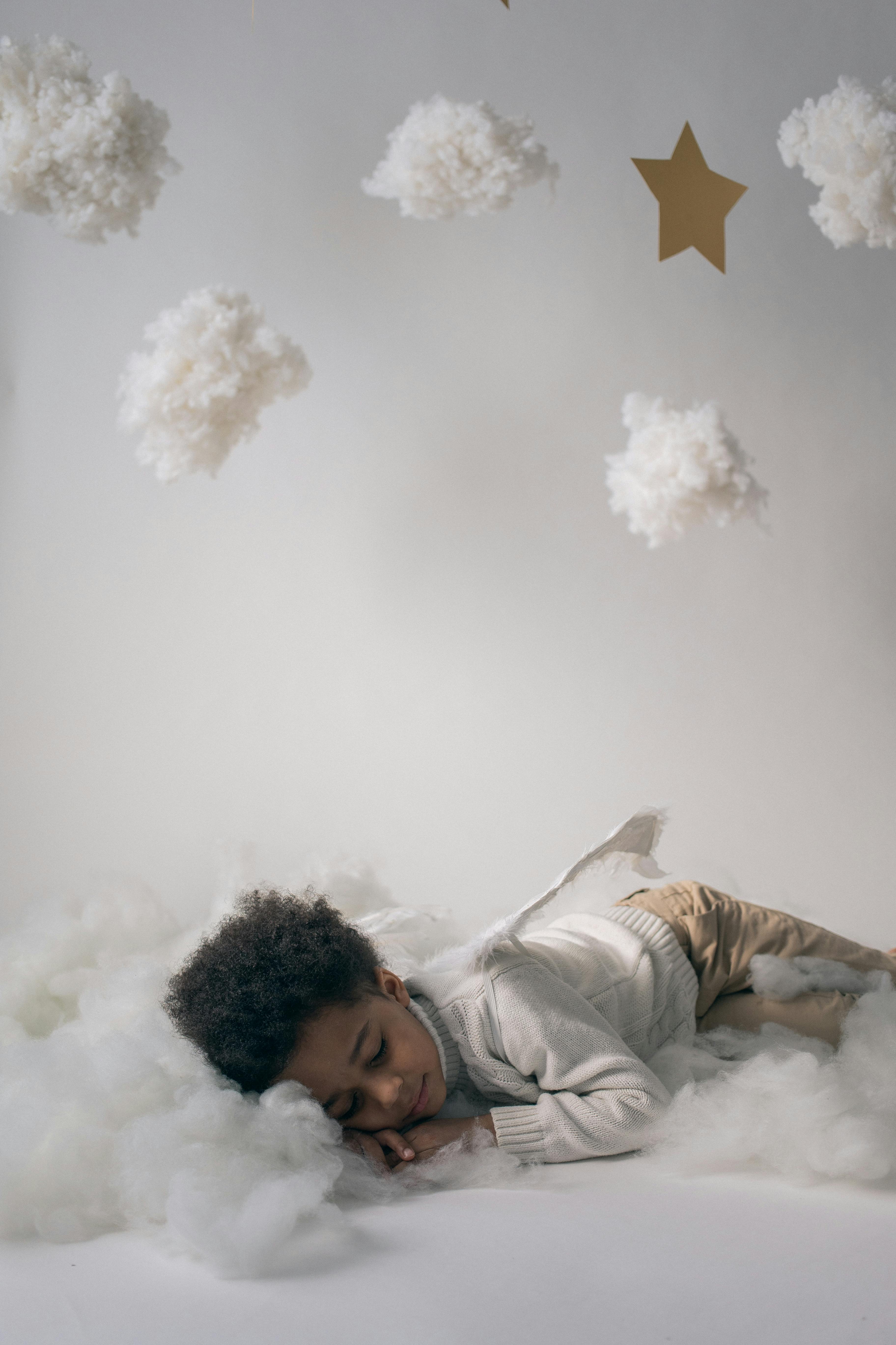 sleepy black boy in angel costume sleeping in decorated studio
