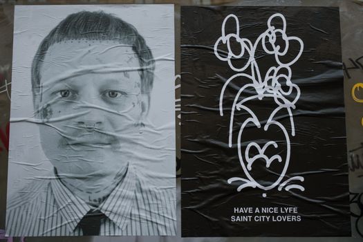 Black and white portrait alongside a graphic floral poster on city street.