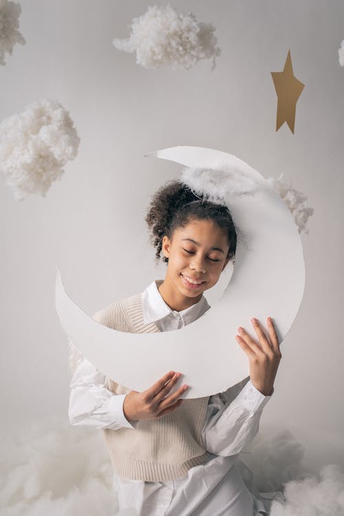 Smiling girl in angel costume holding handmade moon