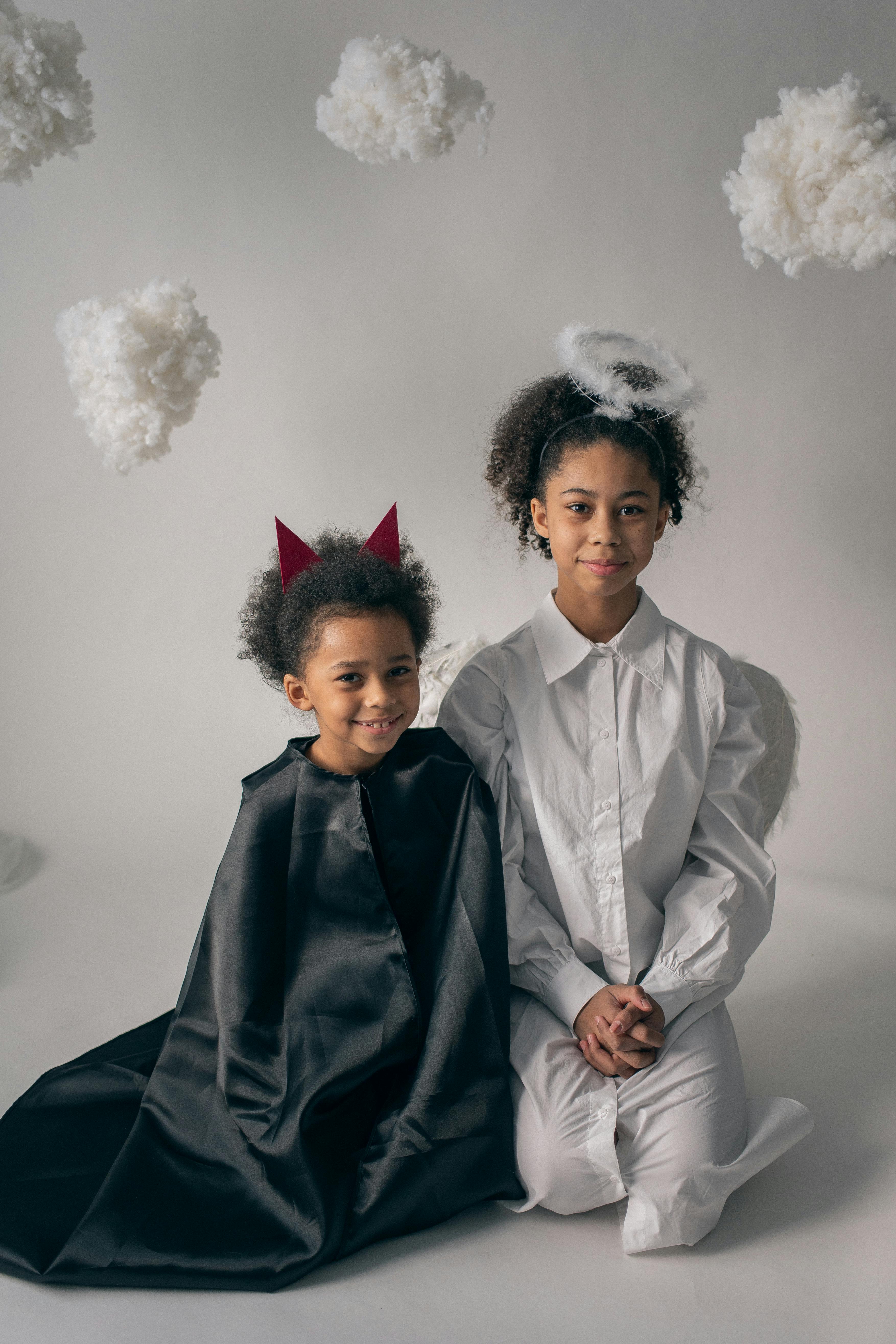 happy siblings in costumes sitting on floor