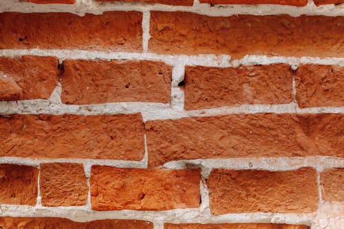 Textured backdrop of bricks between cement layers with uneven surface and dense structure in daytime