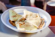 Tasty hotcakes with filling in round shaped plastic plate on table in sunlight on blurred background