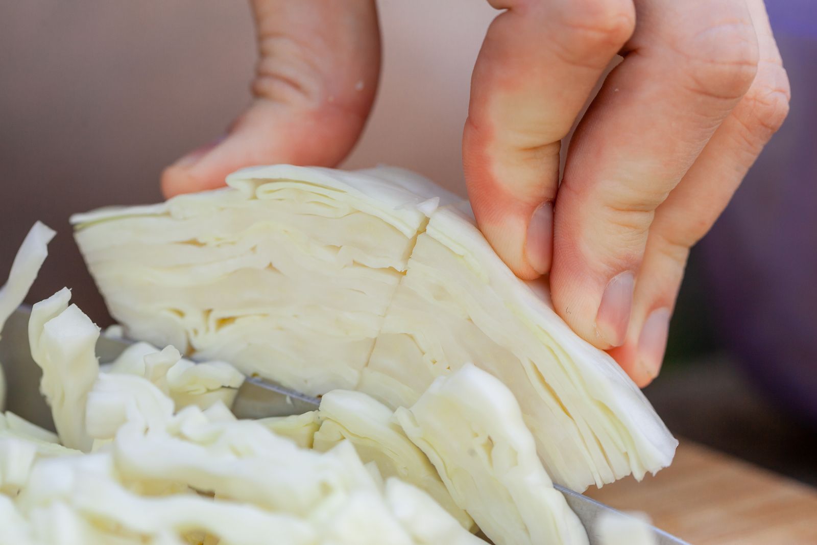 Hands slicing a vegetable on a board with a chef knife