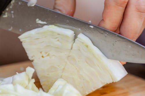 Chef slicing ripe cabbage on cutting board