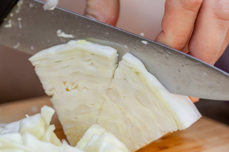 Chef Slicing Ripe Cabbage On Cutting Board