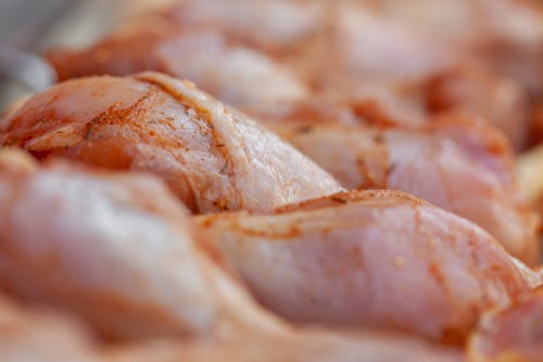Closeup of tasty raw chicken legs with seasoning placed in row in daylight