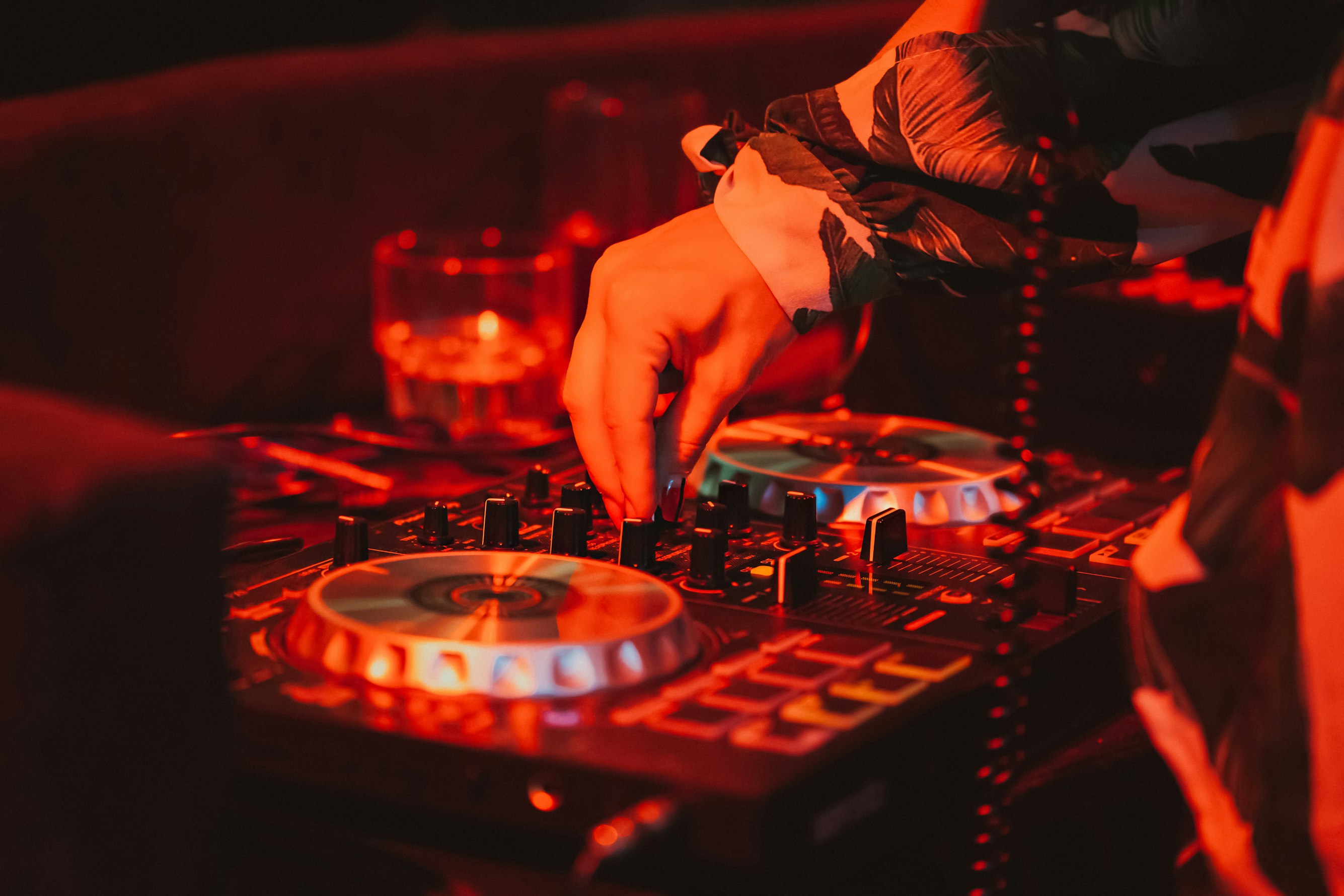 A DJ's hands on a mixer at a vibrant party