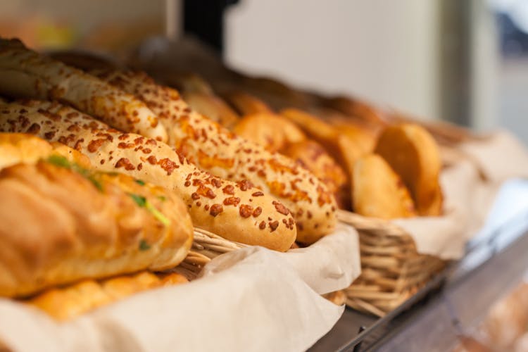 Various Fresh Buns And Bread In Basket In Bakery