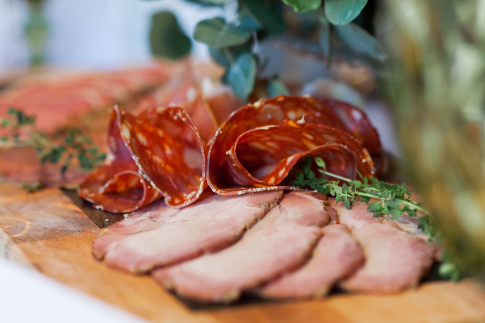 Different deli meats arranged on a rustic wooden platter