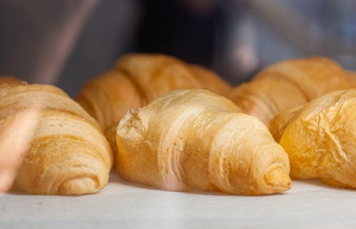 Free Delicious fresh croissants with golden crust placed on white surface in light cafe Stock Photo