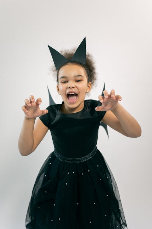 Adorable little ethnic kid showing claws and roaring against white background