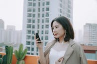 Woman in Brown Blazer listening to Music using Smart Phone