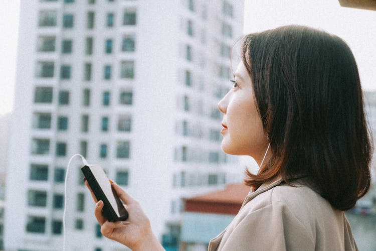 Woman Wearing Earphones Holding A Cellphone