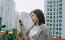 Woman in Brown Blazer listening to Music using Smart Phone