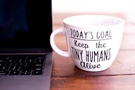 木桌上笔记本电脑的旁边，有一个印着励志文字的马克杯特写