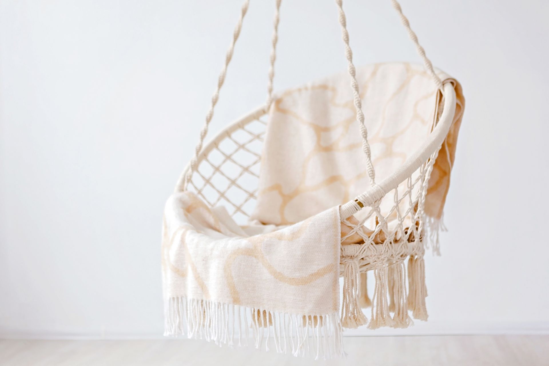 Stylish hanging chair draped with a beige blanket, adding a touch of coziness to a minimalist room.