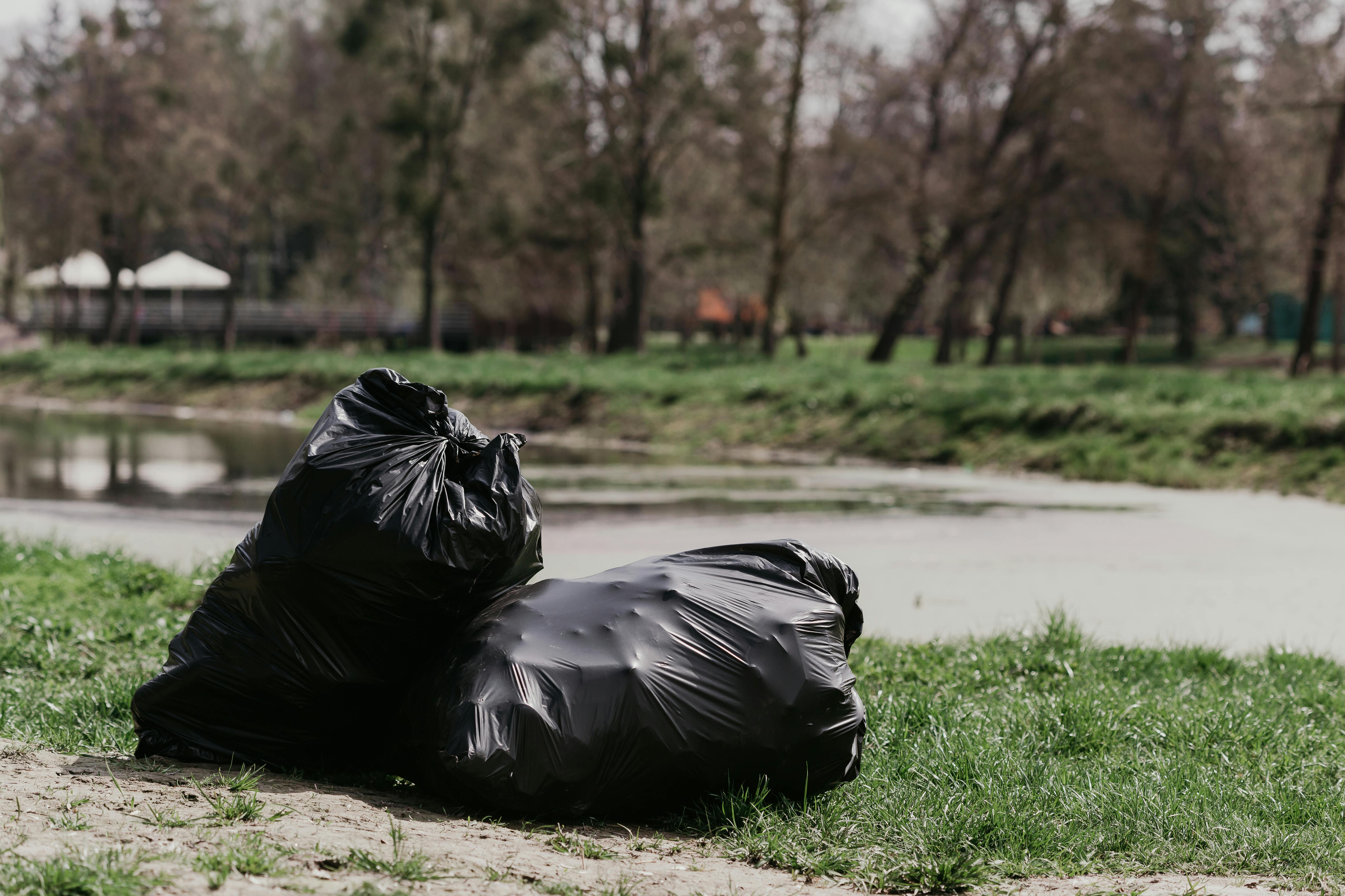 Premium Photo  Big black garbage bags on the green grass.