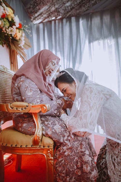 A Bride Kneeling on the Woman in Pink Hijab