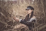 A Woman with a Black Cap Touching Dry Grass