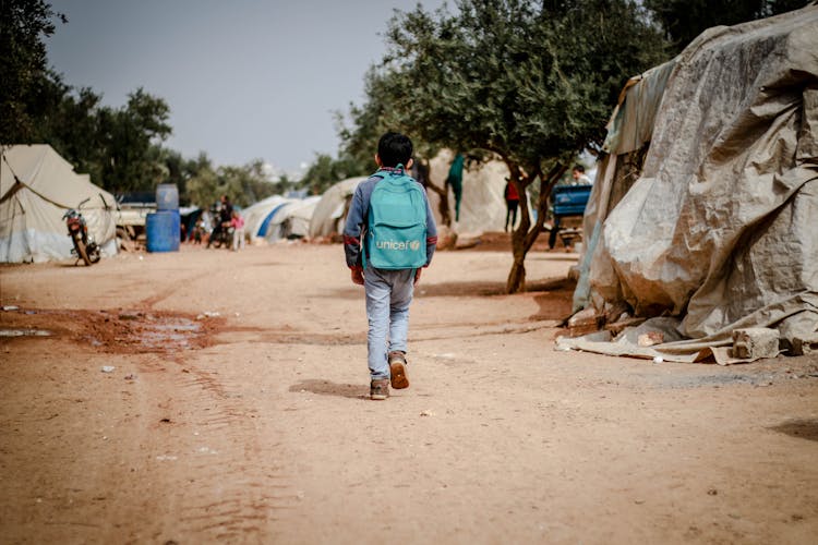 Back View Of A Boy With A Blue Backpack Walking