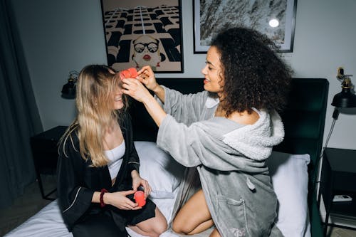 Two Young Women Having Fun Putting Hair Rollers on Their Hair