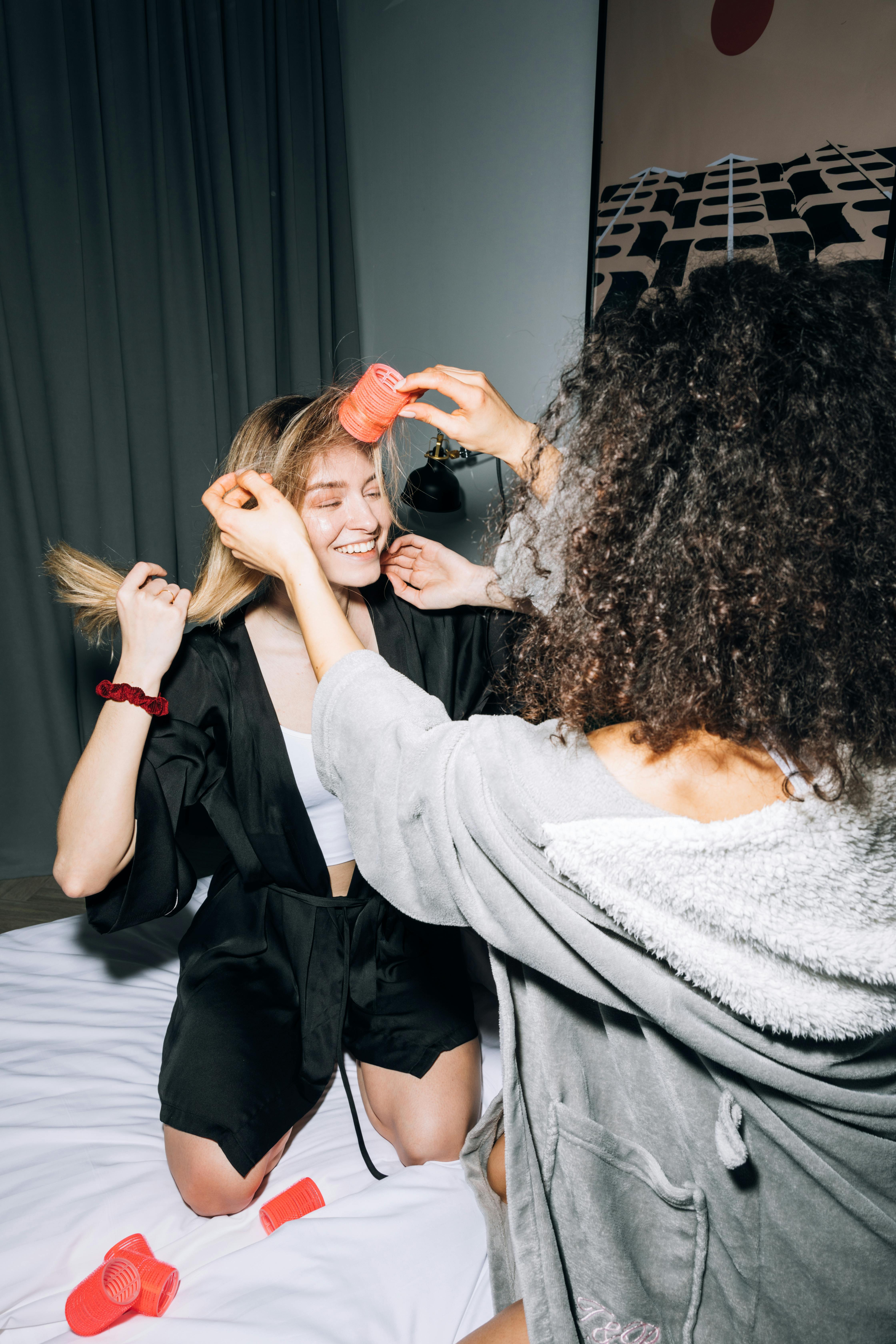 two young women putting hair rollers on their hair