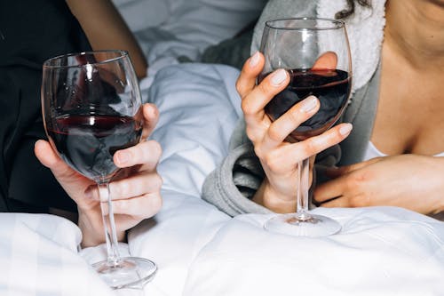 Free Close-Up View of Two Persons Holding a Wine Glass With Red Wine Stock Photo