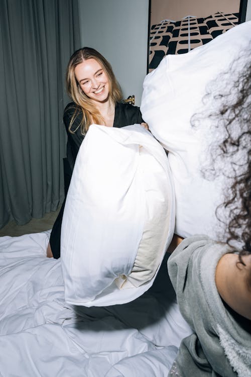 Free Young Woman Having Fun While Doing Pillow Fight Stock Photo