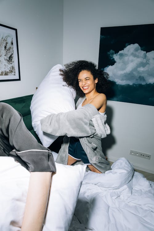 Free Young Woman Having Fun While Doing Pillow Fight Stock Photo