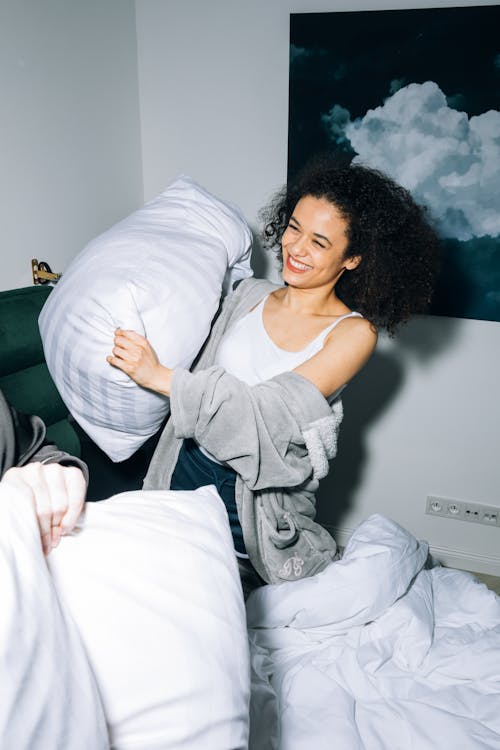 Free Young Woman Having Fun While Doing Pillow Fight Stock Photo