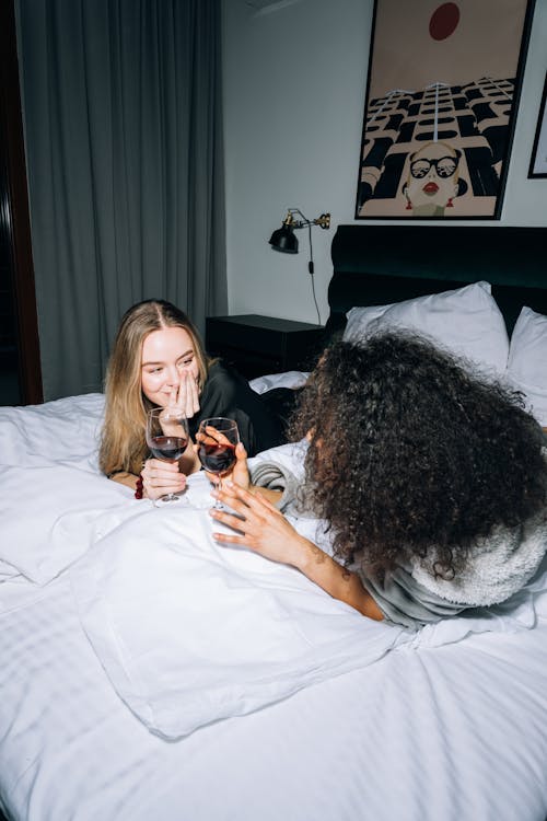 無料 お互いを見ながら白いベッドに横になっている2人の女性 写真素材