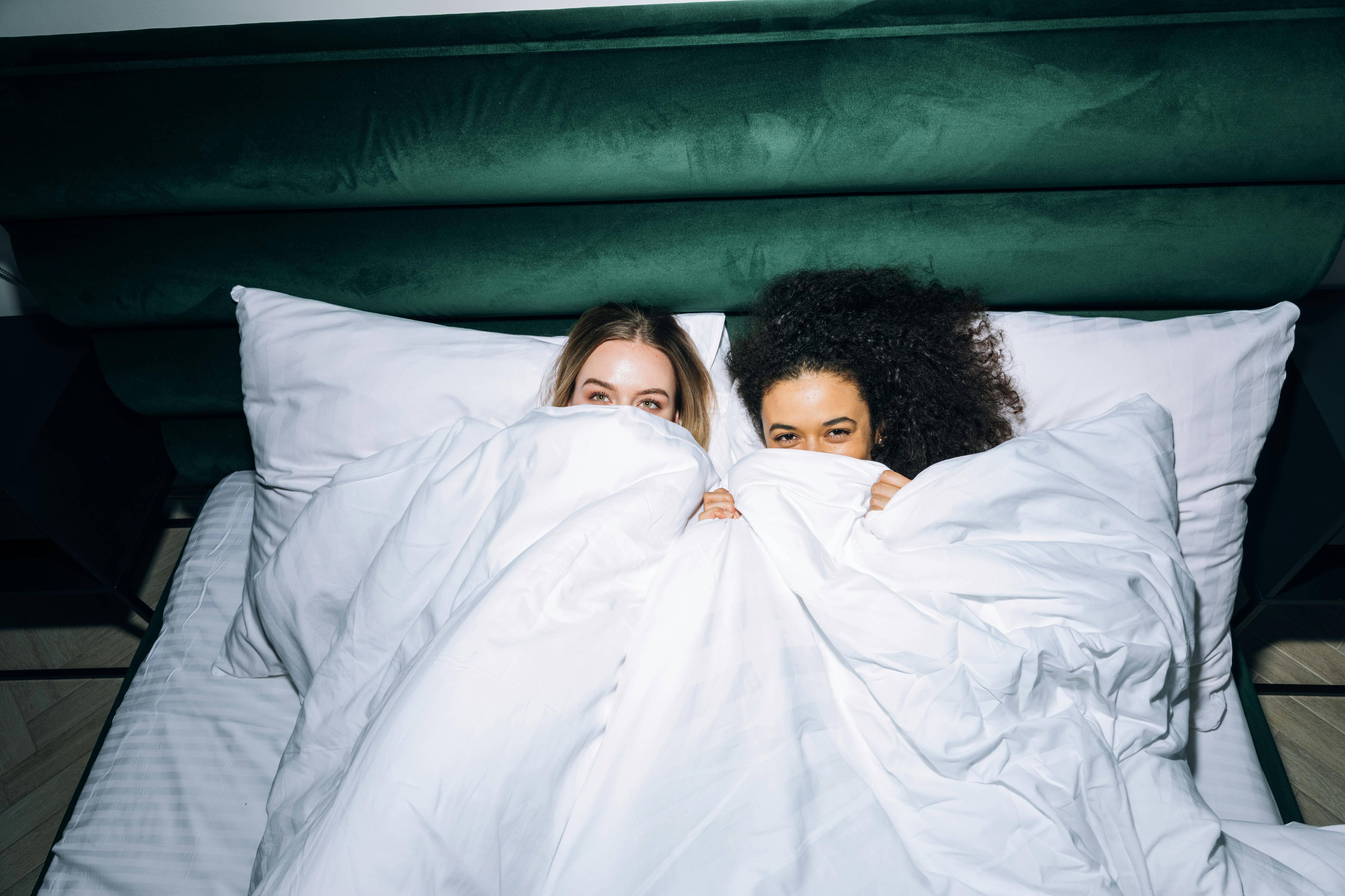 two young women lying on white bed