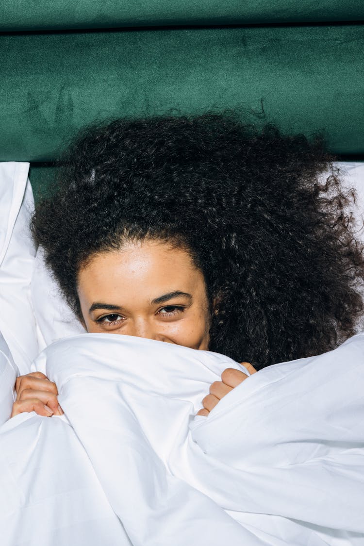 Young Woman Lying Down On White Bed