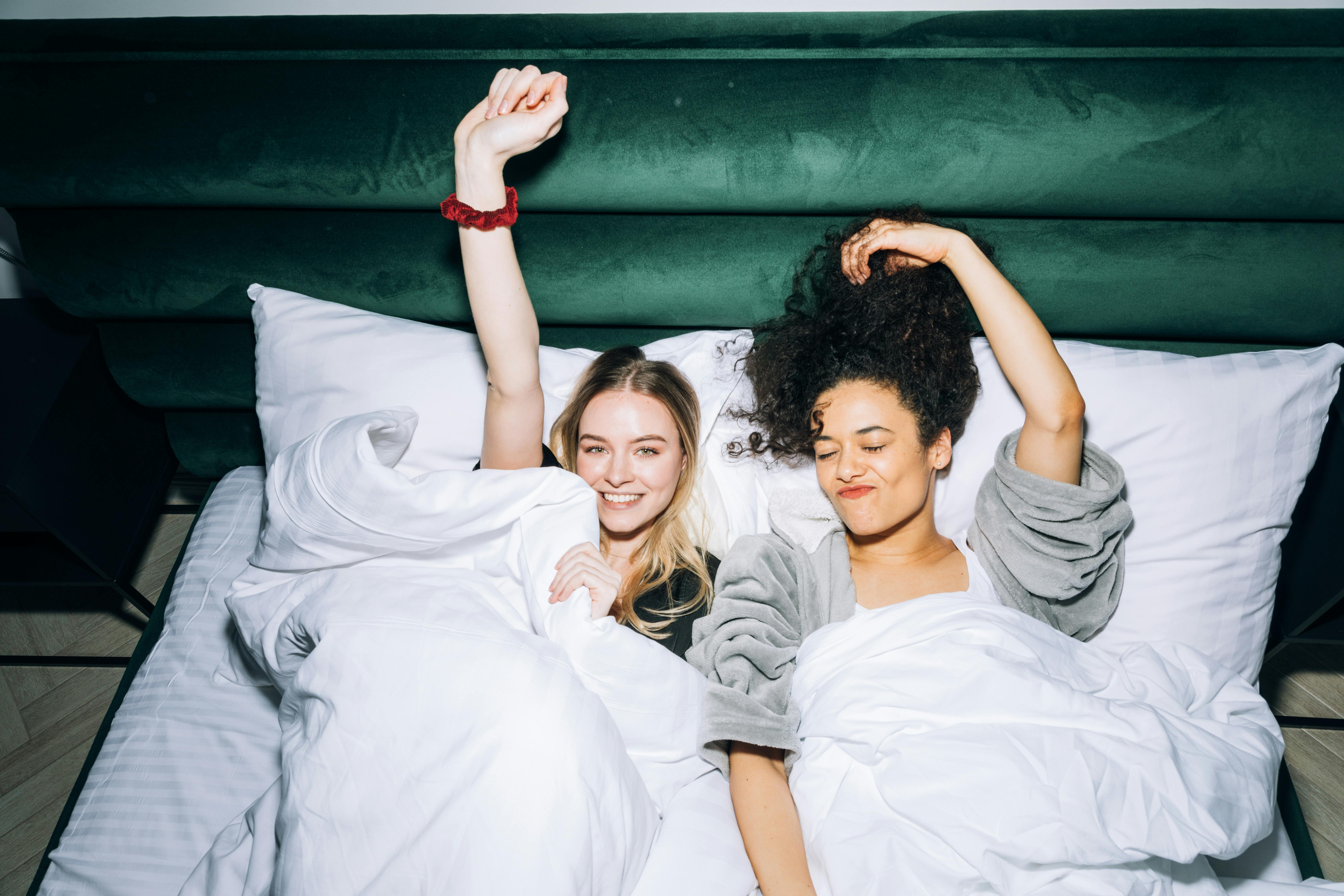 two young women lying on white bed