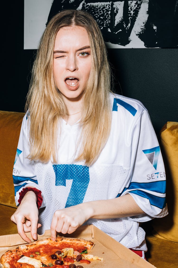 Young Woman Winking While Getting A Slice Of Pizza