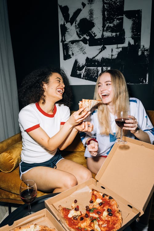 Free Two Young Women Having Fun While Eating Their Pizza Stock Photo