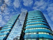 现代摩天大楼的玻璃立面在蓝天下反射出低角度视图