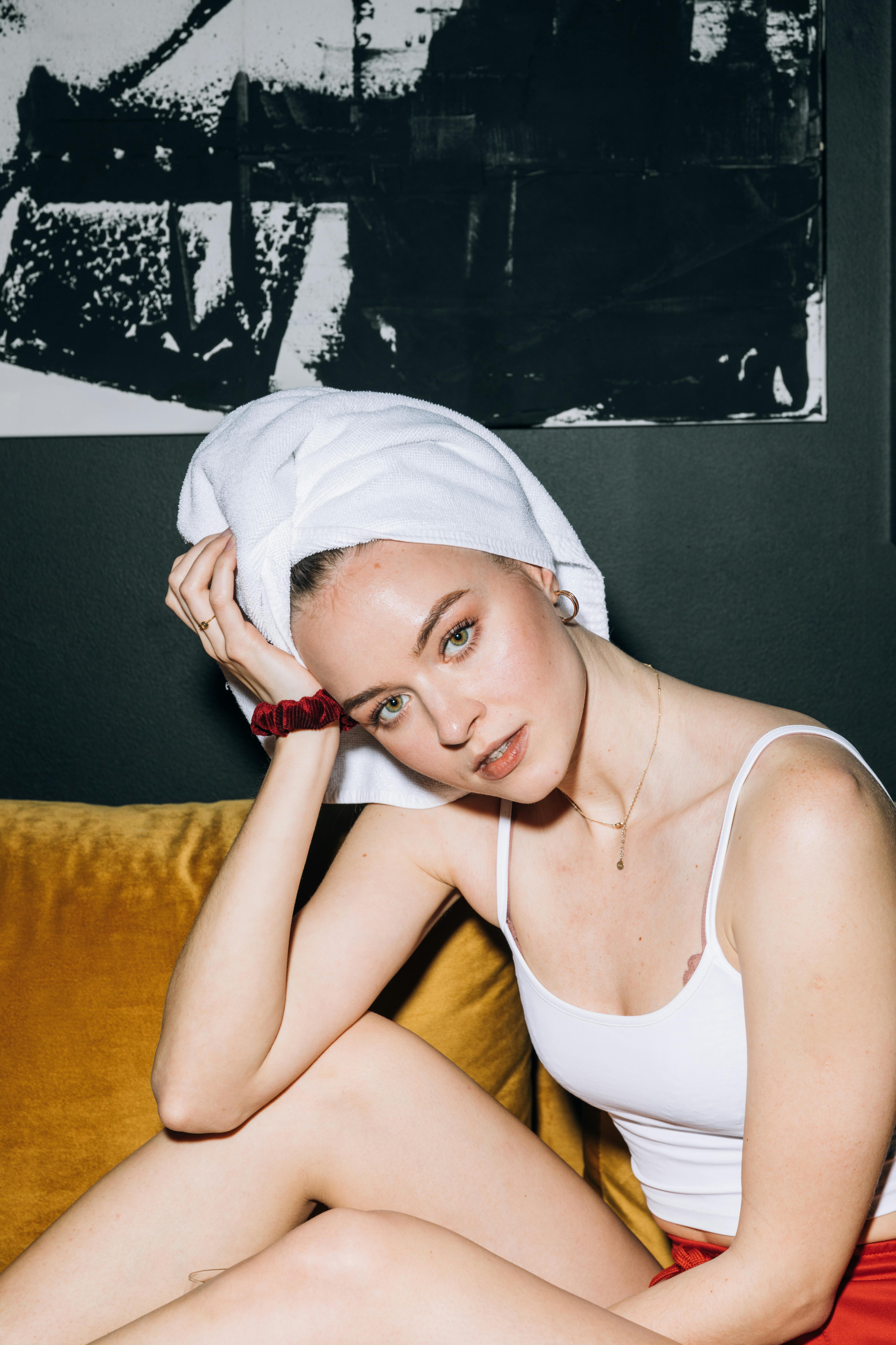 年轻女子裹着毛巾躺在沙发上，散发着现代的优雅和放松