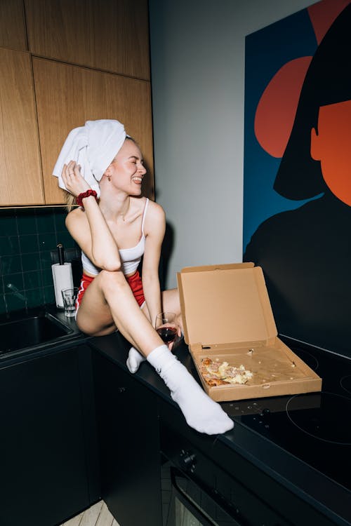 Young Woman Sitting on a Kitchen Counter While Sticking Her Tongue Out