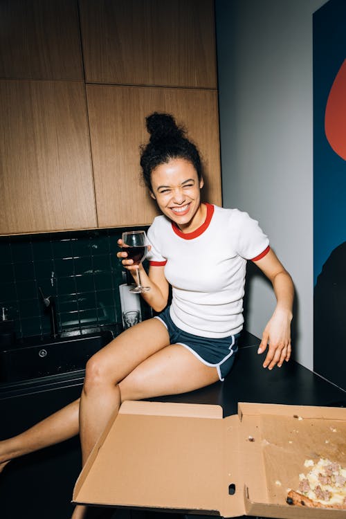 Free Young Woman Smiling While Sitting on a Kitchen Counter Stock Photo