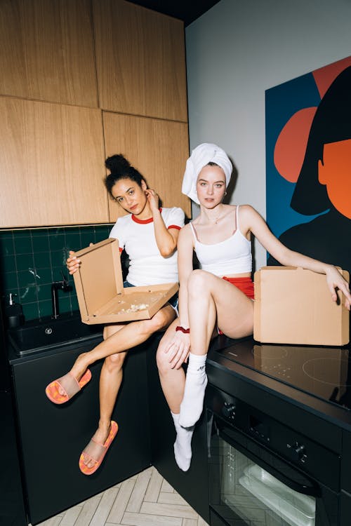 Free Two Young Women Sitting on a Kitchen Counter Stock Photo