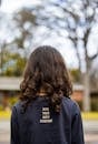 Back view of unrecognizable girl wearing long sleeve t shirt with inscription standing in park