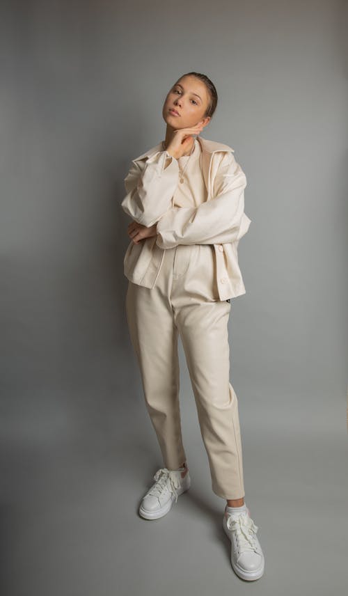 Free Woman in Beige Coat and Pants Standing on Gray Background Stock Photo