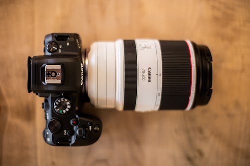 Professional photo camera with lens on wooden table