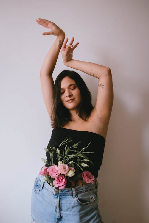 Woman in Black Tube Top with Flowers on her Waist Raising Hands Up